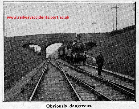 Posed 1930s accident prevention photo, showing a worker standing between tracks, about to be hit by a steam train approaching unseen from behind.