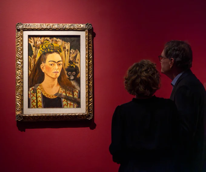 Two museum visitors viewing a self portrait of Frida Kahlo in VMFA's exhibition "Frida: Beyond the Myth."