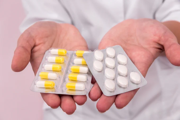 Two hands outstretched with two pill blister packages