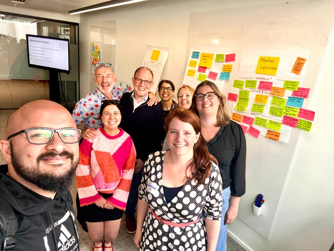 The DiveIn Team with Toby and Emma in front of the poster wall from the workshop