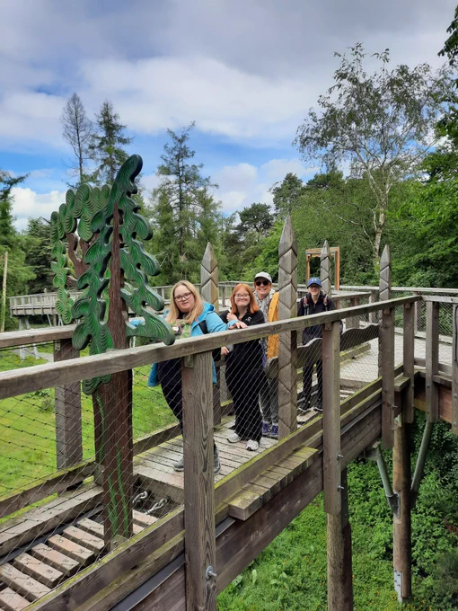 A group of TCPID students and staff walking across a wooden bridge high above the forest