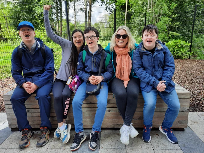 5 people sitting on a wooden bench in the forest