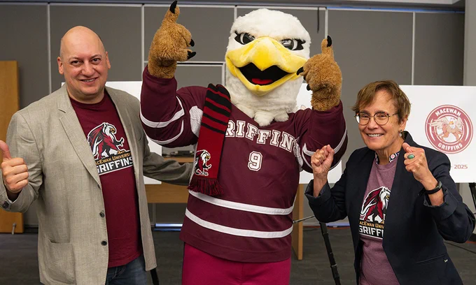 Two people pose with a Griffin mascot.