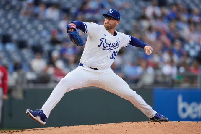 Noah Cameron delivers a pitch in a home white Royals uniform with blue lettering.