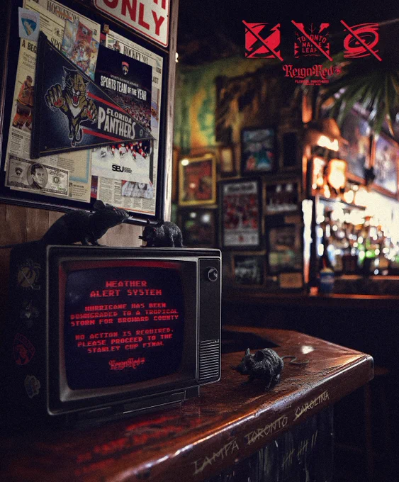 On a bar, sits an old tv with the text in red: “Weather Alert System. Hurricane has been downgraded to a tropical storm for Broward County. No action is required. Please proceed to the Stanley Cup Final.” With the Reign Red logo underneath.
Around the tv are several plastic rats. On the edge of the bar are “Tampa” “Toronto” and “Carolina” scratched out. On the side of the TV are different Florida Panthers logos.
Hanging behind the tv are various memorabilia of the Panthers including a Panthers leaping cat flag, Matthew Tkachuk on a $100 bill, and a poster of our recent Sports Team of the Year award.
In the top right, the Lightning, Maple Leafs, and Hurricanes logos are in red with a line through them.