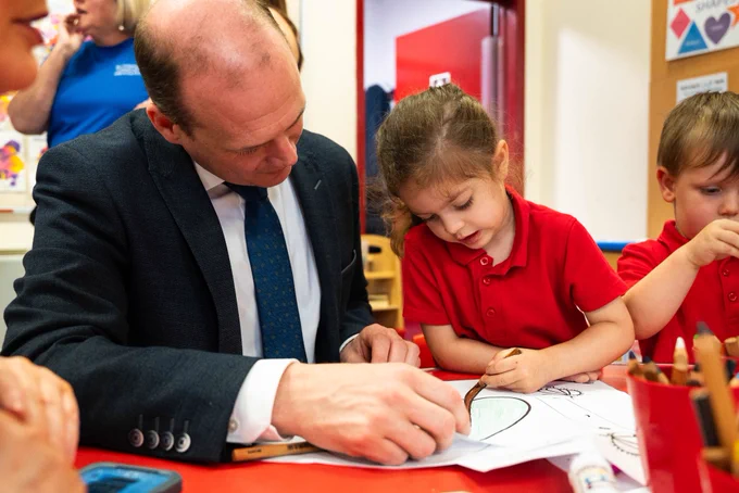 Minister Lyons and a child colouring in.