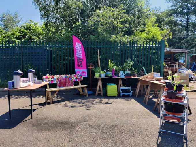 An image of a decorated Say Hello bench with a Say Hello banner flag, plants and refreshments