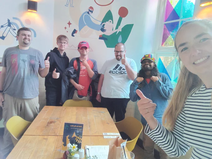 Selfie showing 6 individuals smiling and giving the thumbs up.