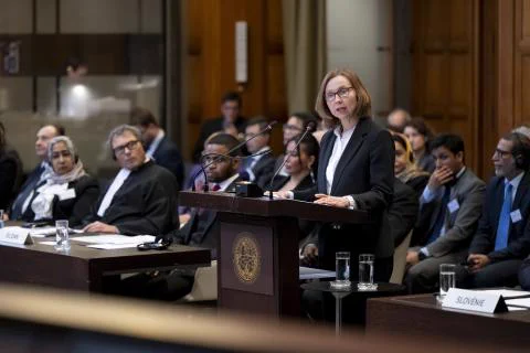 Sally Langrish standing at the podium at the International Court of Justice with a delegation sitting behind her.