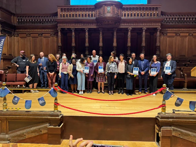 Impact Festival nominees and award winners on stage at the McEwen Hall. Professor Deborah Fry of Childlight is in the centre holding a certificate. 