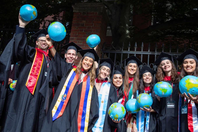 Graduates posing for a photo and holding inflatable globes.