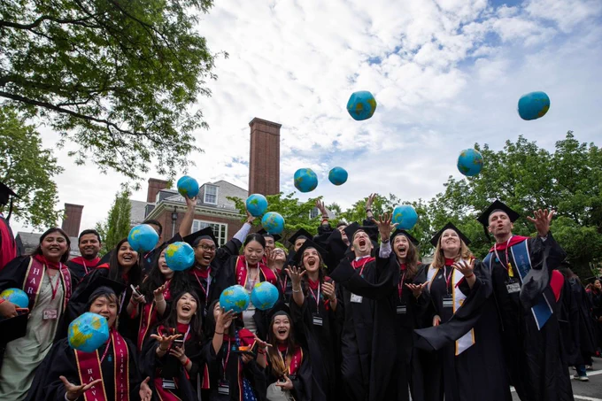A group of graduates throwing inflatable globes in the air.
