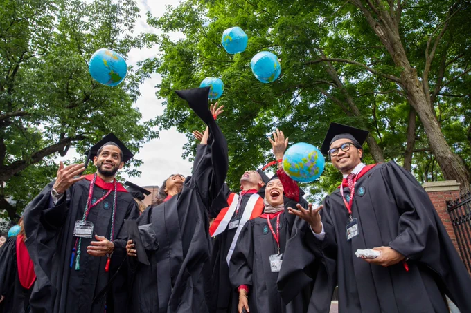 Graduates cheering and throwing inflatable globes in the air.