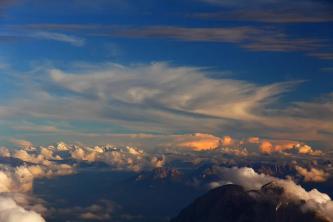 Ein Foto zeigt Cirrus- und Cumuluswolken über den Alpen im Abendlicht. Quelle: Claudia Hinz