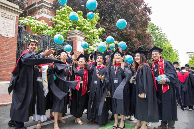 Graduates cheering and throwing inflatable globes in the air.