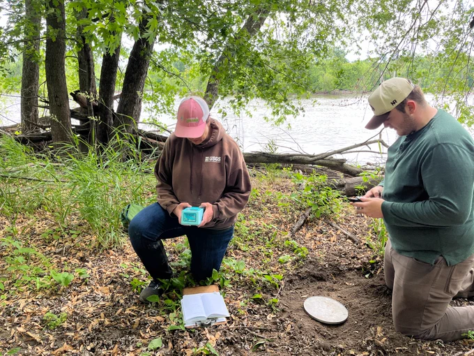 Hydrologist Emilia Bristow and Student Trainee Logan Stewart conduct field work on the shores of the Cedar River in Cedar Rapids, Iowa.