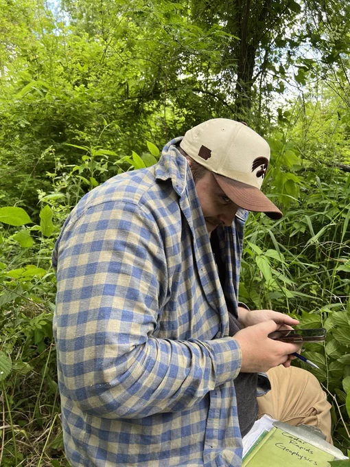 Student Trainee Logan Stewart conducts field work on the shores of the Cedar River in Cedar Rapids, Iowa, while hiding from the mosquitoes!