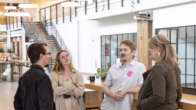 Three Bytes.co employees talking with another woman at the Frank: AI Lab
