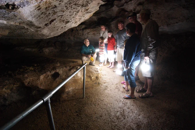 group of visitors exploring Ozark Caverns by lantern light