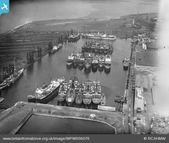 1921 aerial photograph of Queen Alexandra Dock, Cardiff. Showing around 25 cargo vessels in the dock, with railway sidings and coal tips to the sides. Coastline in the distance. Photo courtesy Britain from Above.