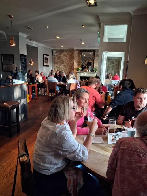 Half a dozen quiz teams gathered around tables in a pub, with the bar to one side.