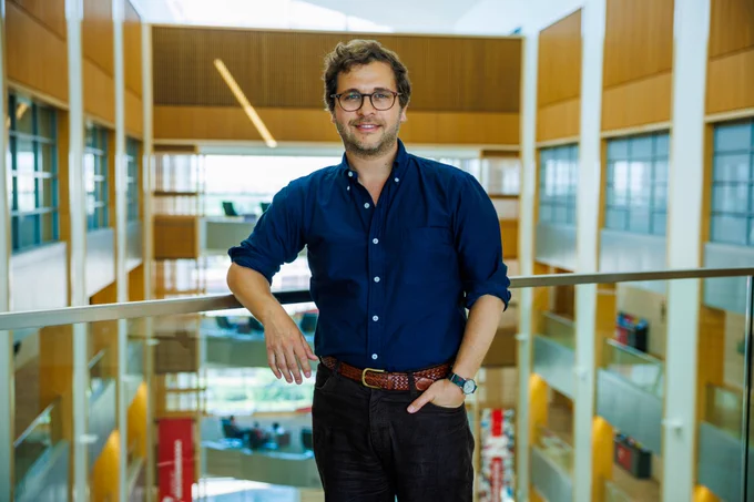 Daniel Tannenbaum, Georgia and Jim Thompson Associate Professor of Economics, stands next to a rail around the atrium to Howard L. Hawks Hall. (Kristen Labadie/University Communication and Marketing)