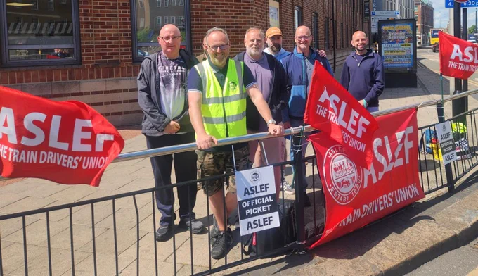 ASLEF members on an official picket line surrounded by red ASLEF flags