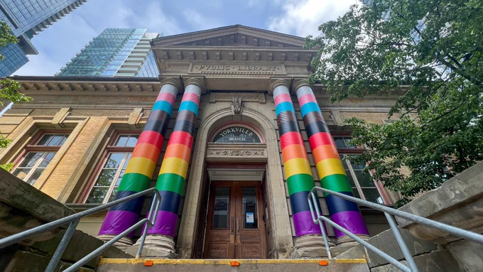 Front of the Yorkville branch. The columns that frame the entrance – two on either side of the door – are wrapped in the Progress Pride Flag. 