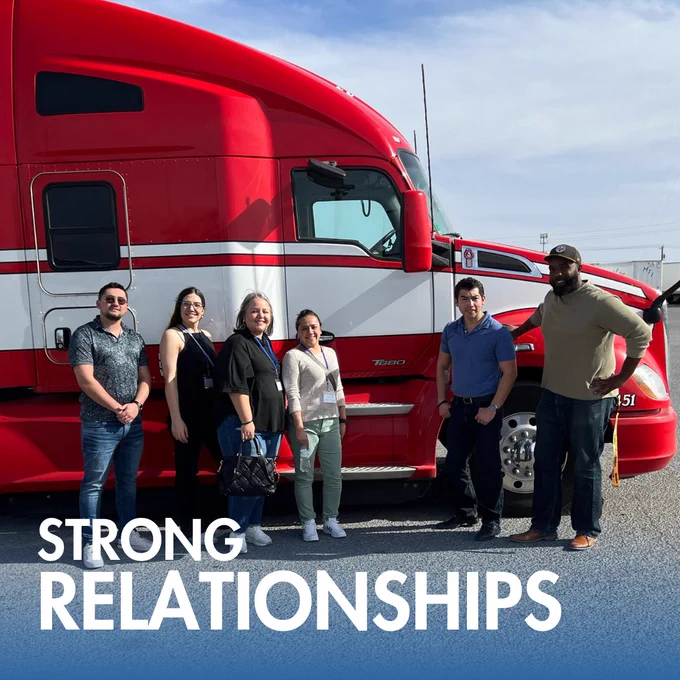 C.A.T. Global SATX team standing next to a red semi-truck in a carrier yard, highlighting the strong relationships built through face-to-face visits with trusted partners.