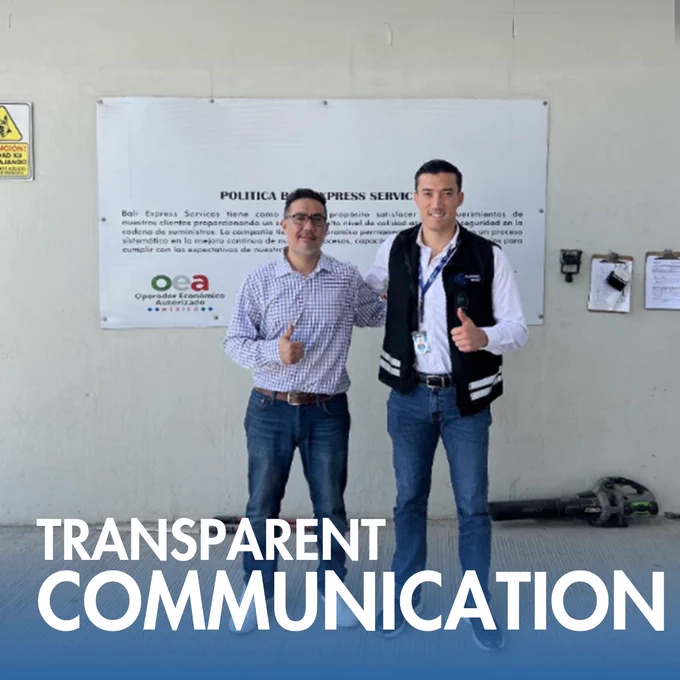 Two logistics professionals standing in front of a sign showing OEA (Authorized Economic Operator) certification, representing the commitment to clear communication and international standards.