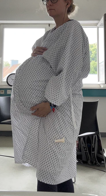 Frau im OP Mantel mit Babybauch
