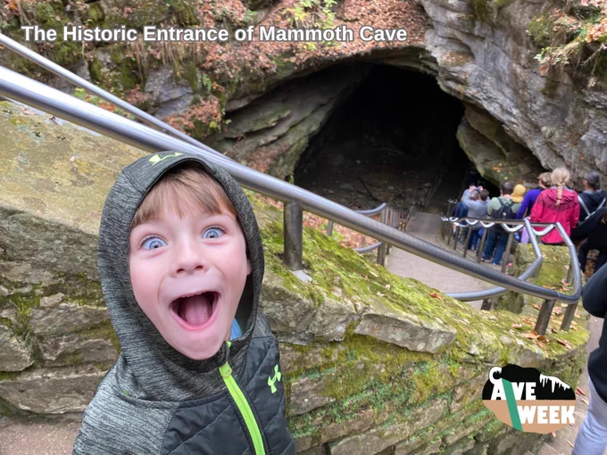 Photo. Little boy with a wide-eyed, big grin standing at the top to the historic entrance to Mammoth Cave. Text says "The Historic Entrance of Mammoth Cave." Cave Week logo in bottom right.