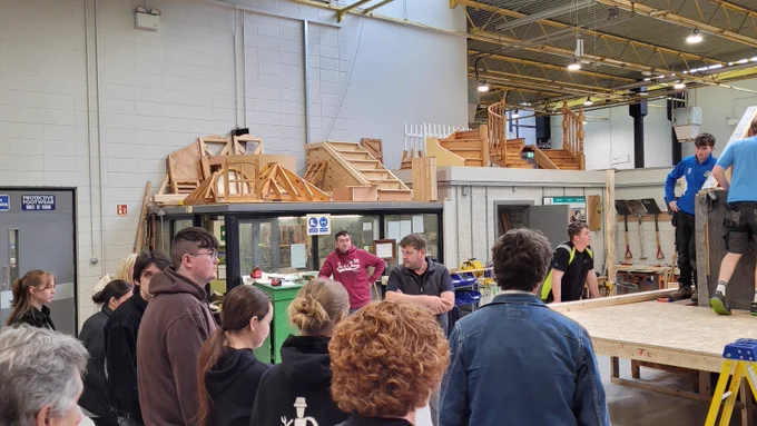 People watching others in a carpentry workshop. 