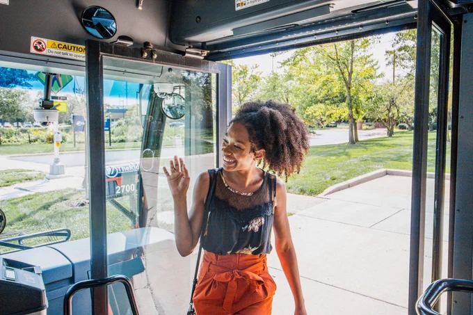 Rider waving to driver as bosarding the bus.
