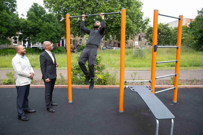 Mayor Lutfur Rahman and Cllr Hussain (left) watching a person using the exercise equipment