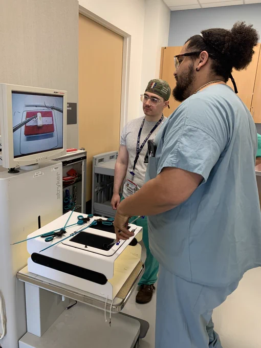 Two people from the surgery residents' group practice their suturing skills.