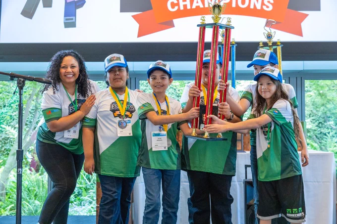 Photograph of Elementary Division champions wearing esports jerseys and holding up their trophy.