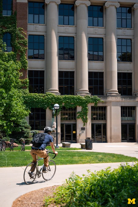 A U-M student cycling through Central Campus.