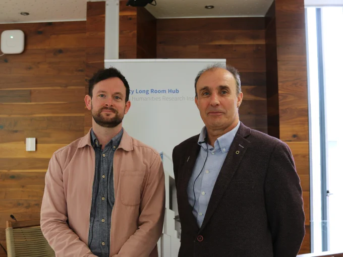 Dr Ciaran O’Neill (left) and Ciarán Murray (right) standing side by side in front of a Trinity Long Room Hub banner. Both are wearing clip-on microphones, following their recorded conversation for the Trinity Talks: Dublin’s Hidden Histories series.