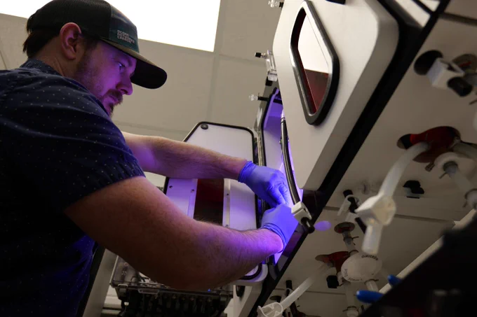 A person wearing gloves operates equipment inside Seaweed Innovation Lab. 