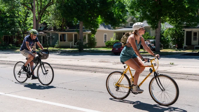 Two festivity attendees biking down the street in summer clothing