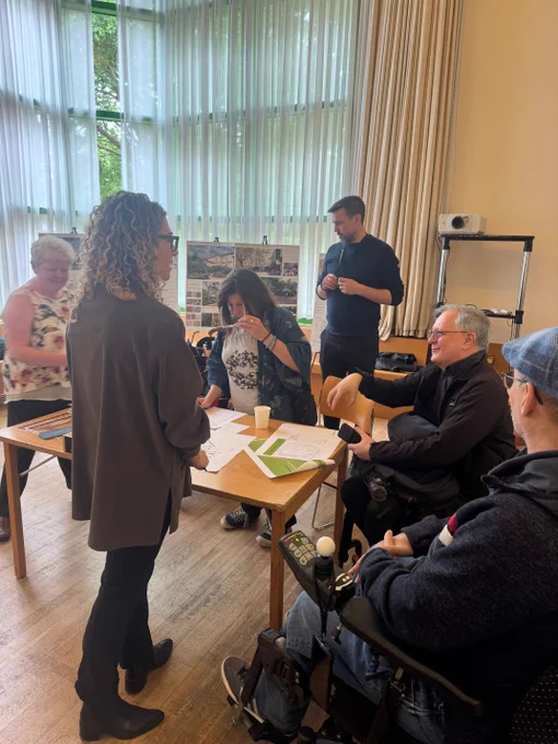A mixed group of adults gathered around a table looking at documents.