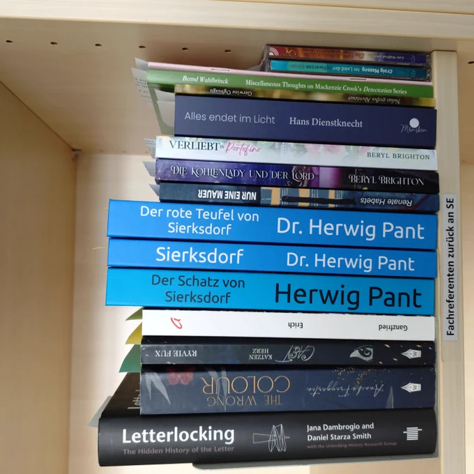 foto einiger bücher in einem regalfach; zu besseren lesbarkeit der titel auf den buchrücken wurde das foto um 90 grad nach links gedreht