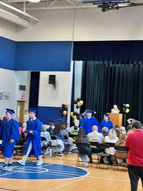 students, families and staff celebrating graduates in the nsa gym