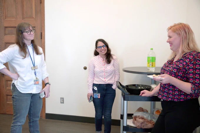 [ID: Pictured is a photo of UTA Libraries staff member Lainie Allen, visiting with staff members.]