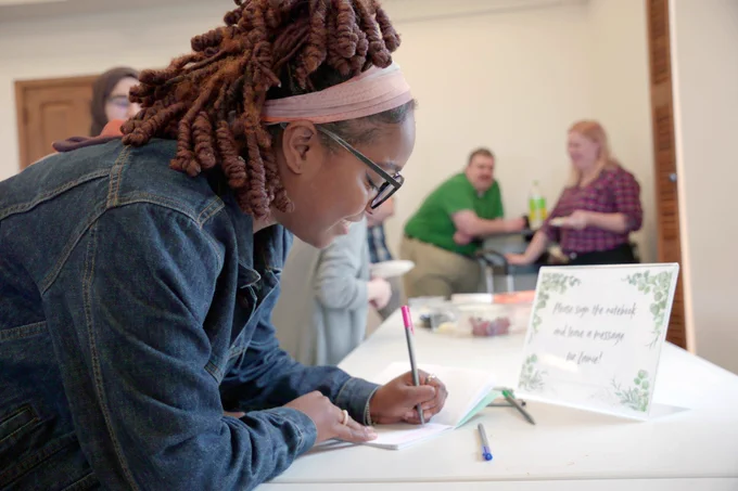 [ID: Pictured is a photo of a UTA Libraries staff member writing a note in a book.]