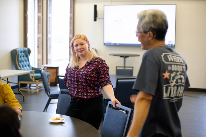 [ID: Pictured is a photo of UTA Libraries staff member Lainie Allen, visiting with staff members.]