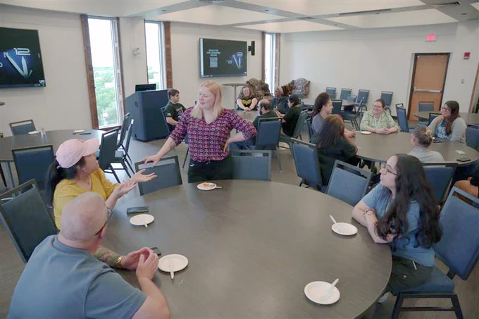 [ID: Pictured is a photo of UTA Libraries staff member Lainie Allen, visiting with staff members.]