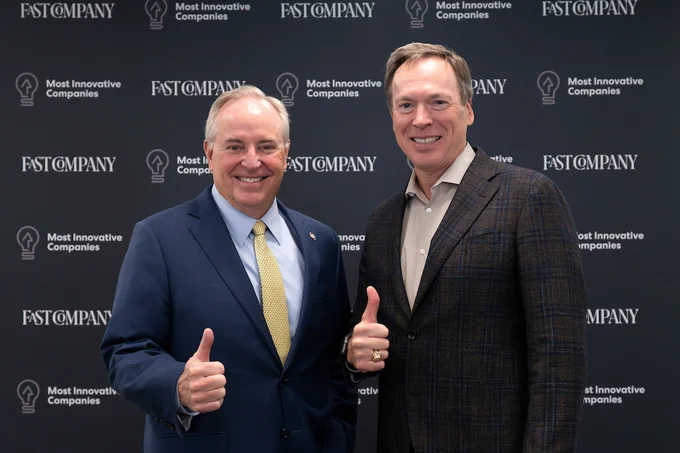 Texas A&M President Mark Welsh and Dean Tim McLaughlin posing with thumbs up in front of a backdrop with the Fast Company logo and the text "Most Innovative Companies.
