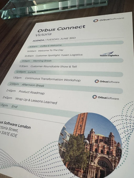 A printed agenda for the 'Orbus Connect Victoria' event on June 3, listing sessions such as 'Customer Spotlight: Yusen Logistics' and 'Continuous Transformation Workshop,' placed on a wooden table. 